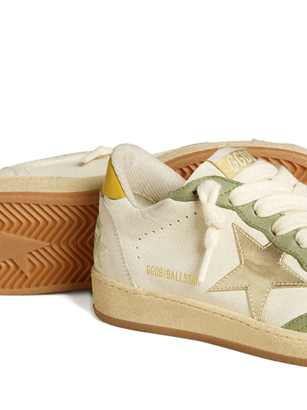 White leather sneaker close-up with star panel, tan sole, green lace guard