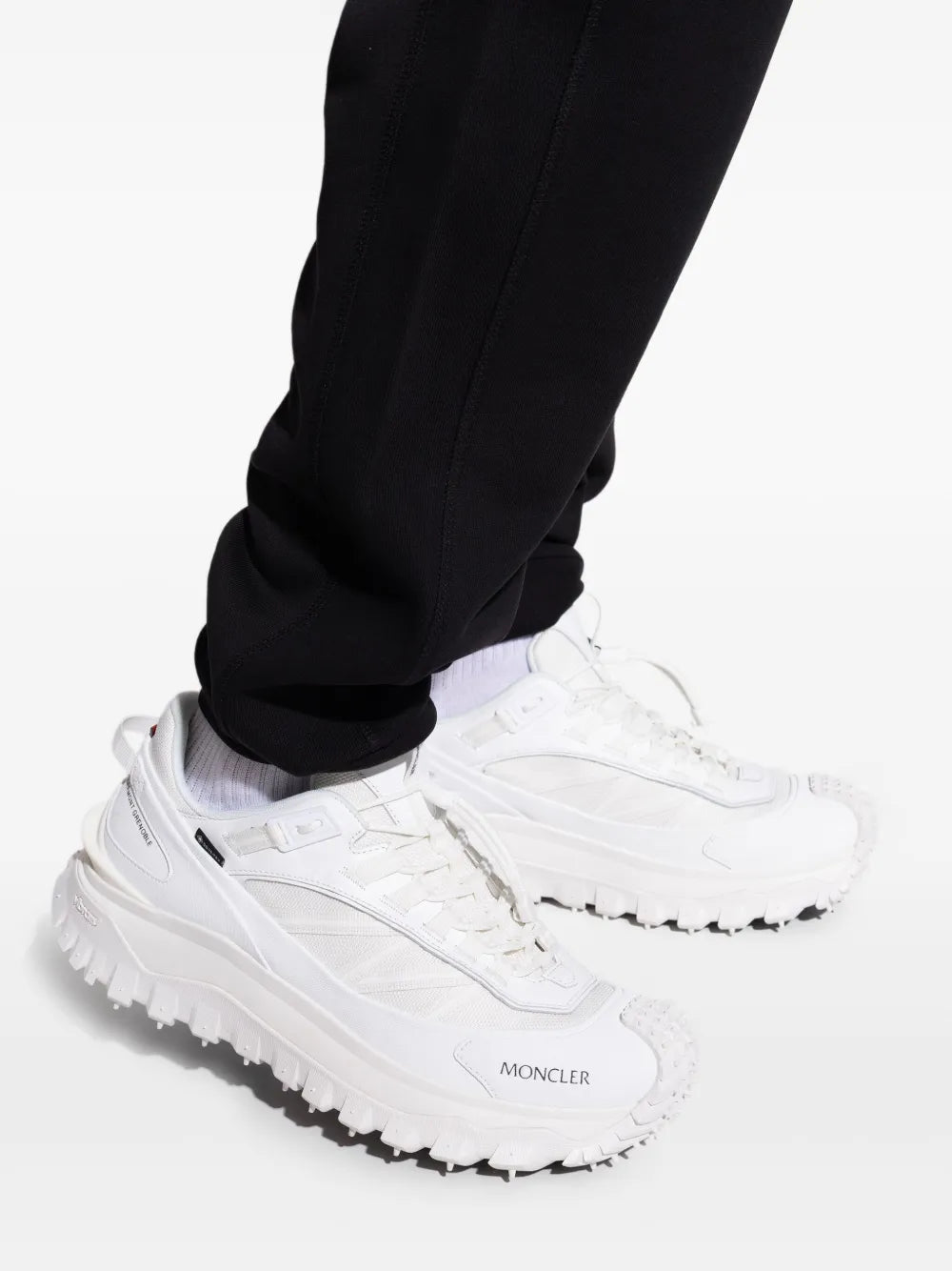 Moncler white Trailgrip GTX sneakers on foot with black pants visible