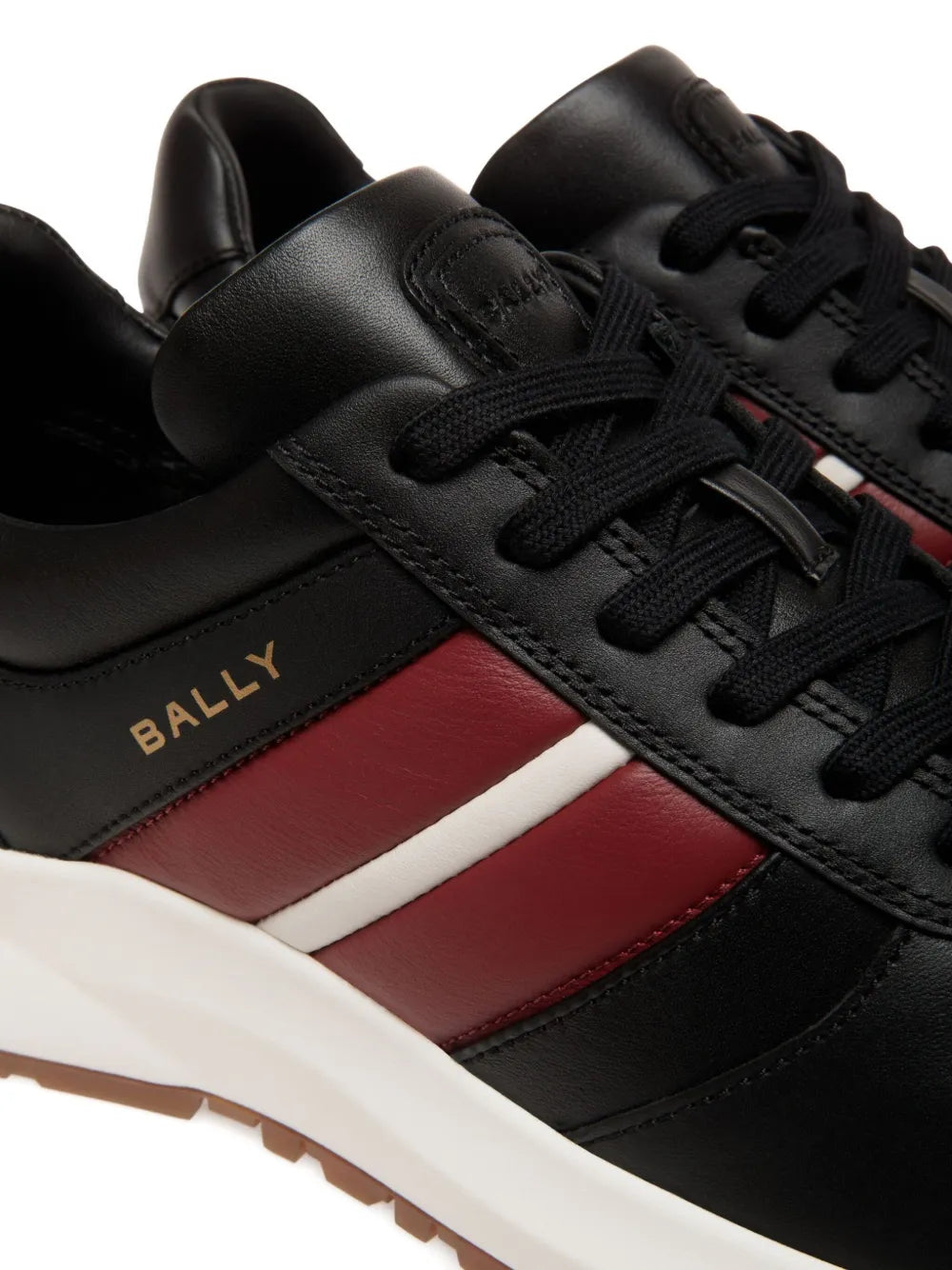 Close-up of black leather lace-up sneakers with Bally stripe and red/white panel