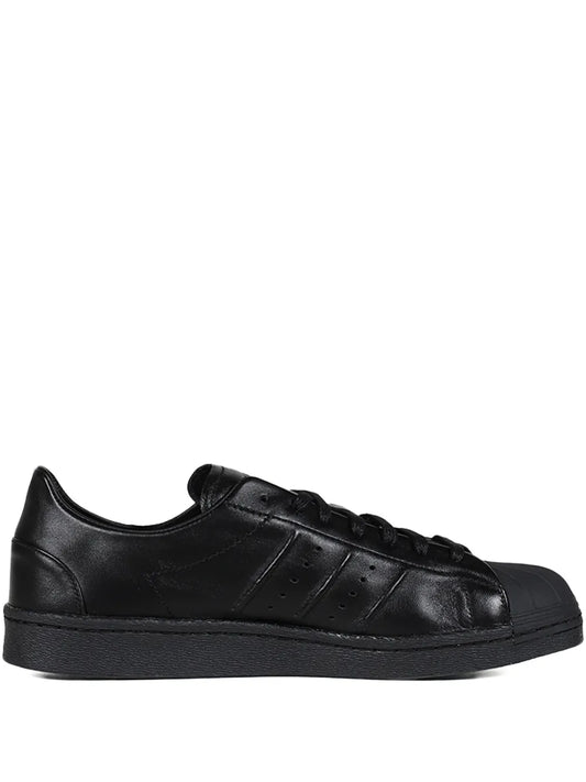 Black leather low-top lace-up sneakers with textured side stripes and rubber sole
