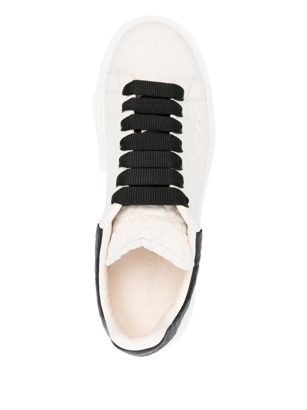 White sneaker top view with black lace-up eyelets and thick sole