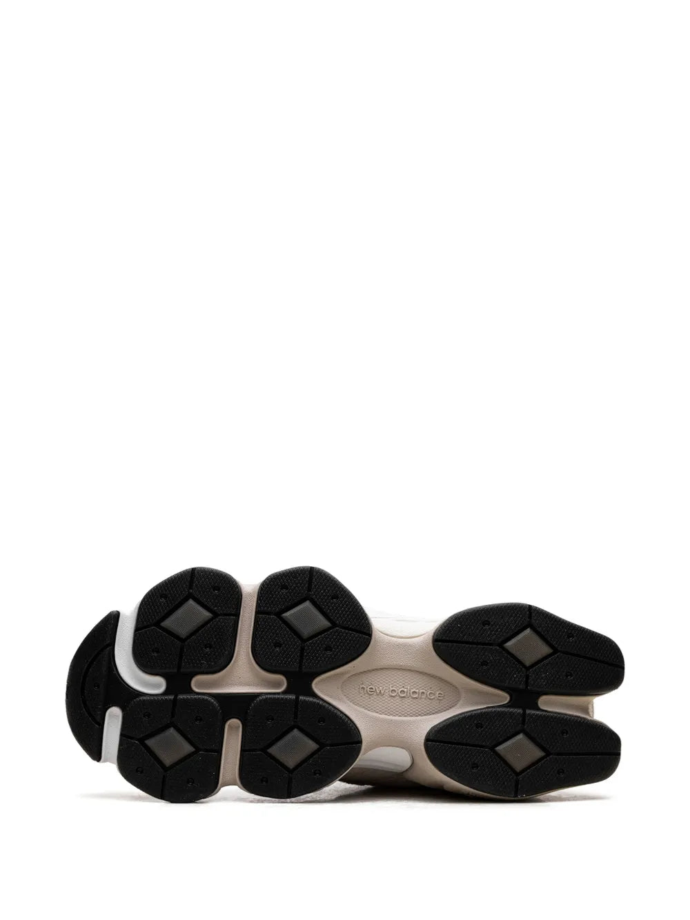 Sneaker outsole with black tread and textured grip on beige midsole.