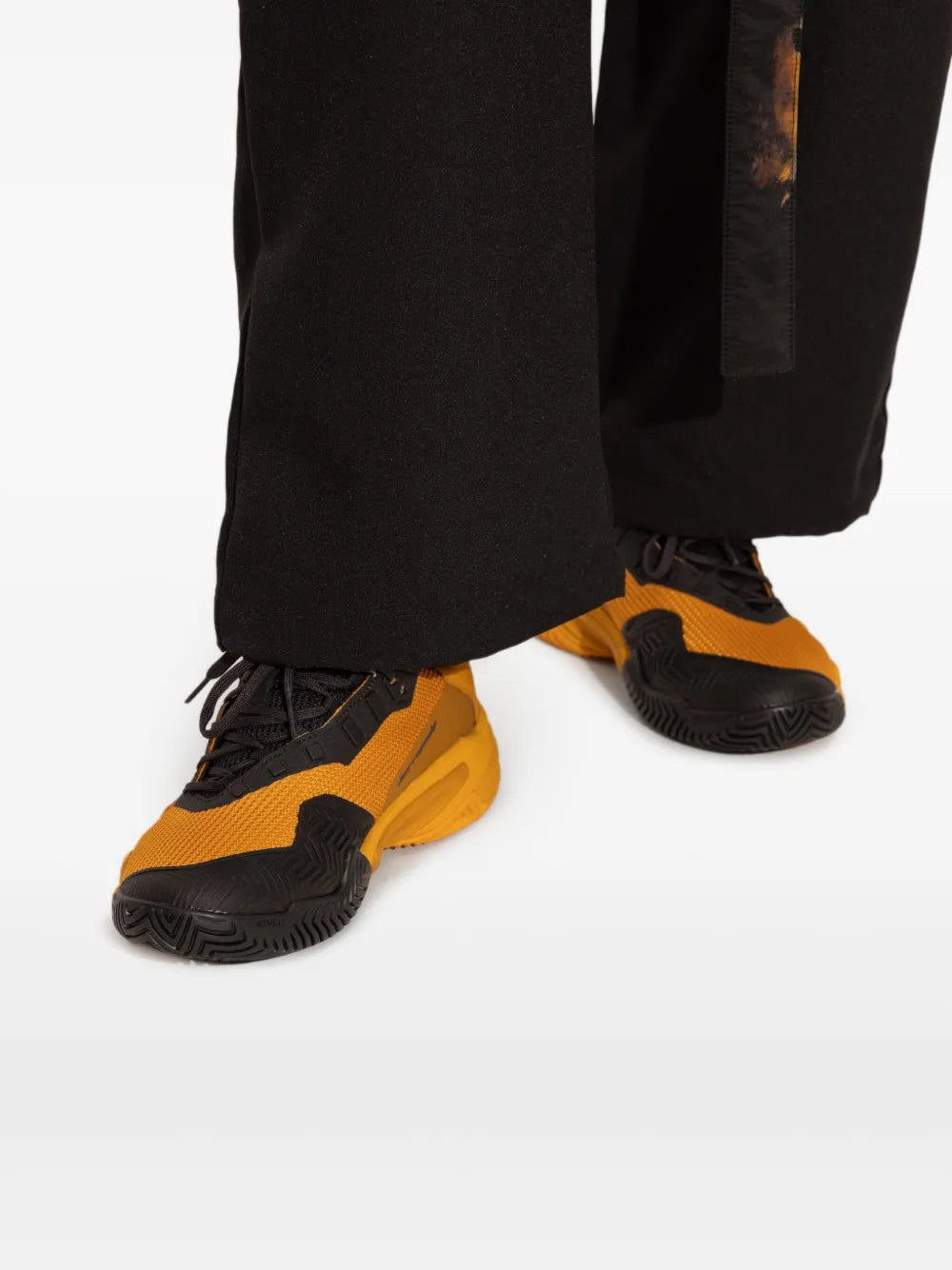 Y-3 orange and black tennis sneakers worn with black pants