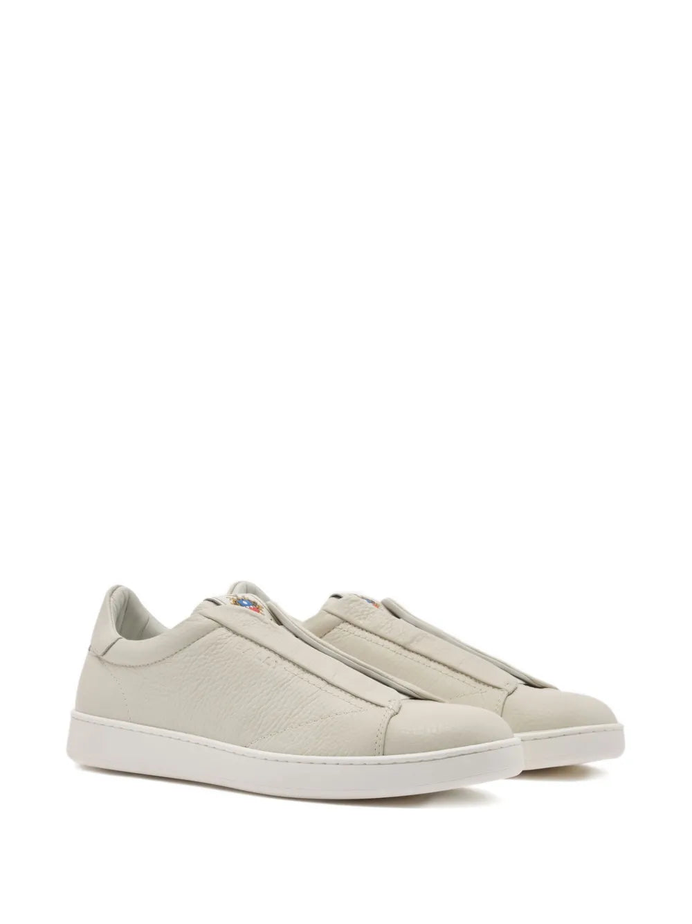 Beige leather slip-on sneakers with stitched side stripe details and rounded toe