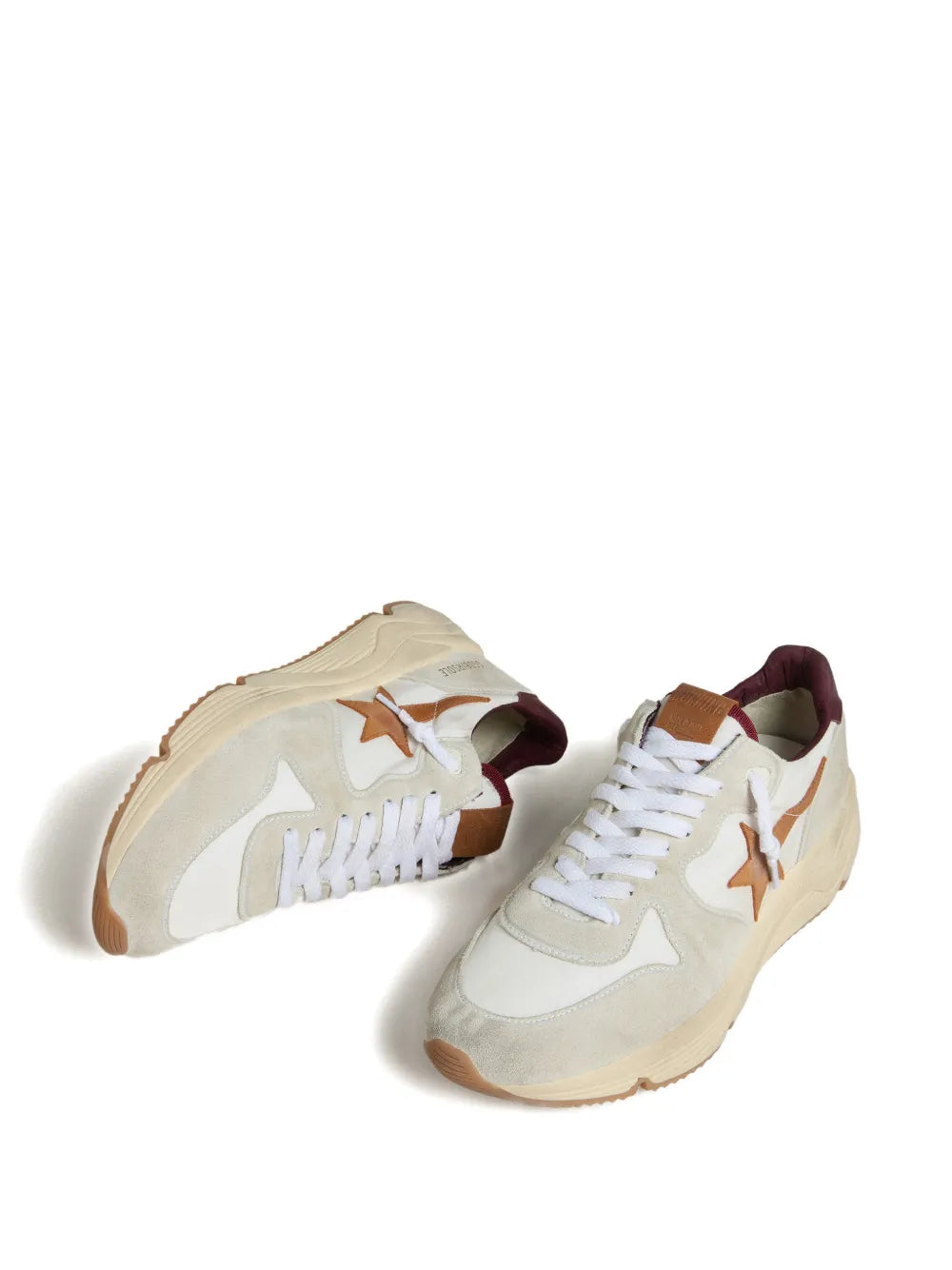 Pair of white sneakers with orange star logos and lace-up uppers