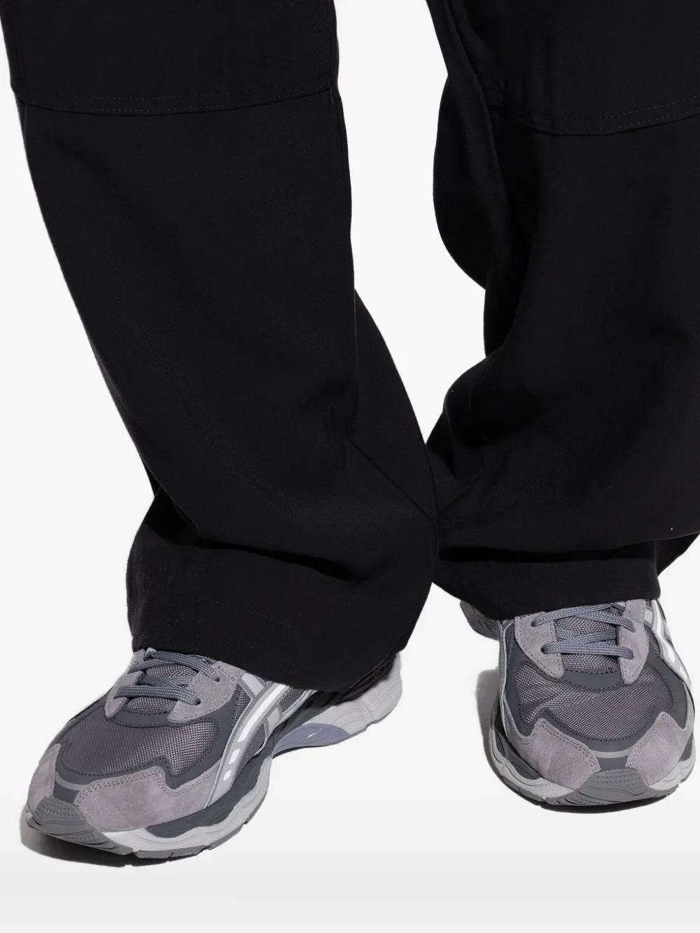 Grey Asics sneakers worn with black pants, showing lace-up and chunky sole