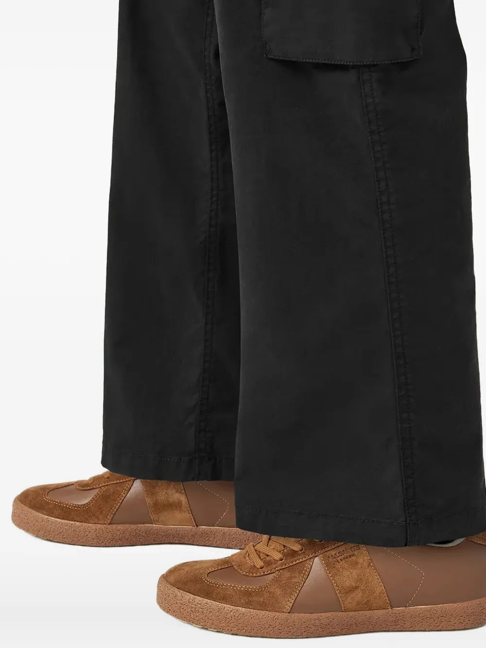 Brown lace-up sneakers worn with black pants, side panels and tan rubber sole visible