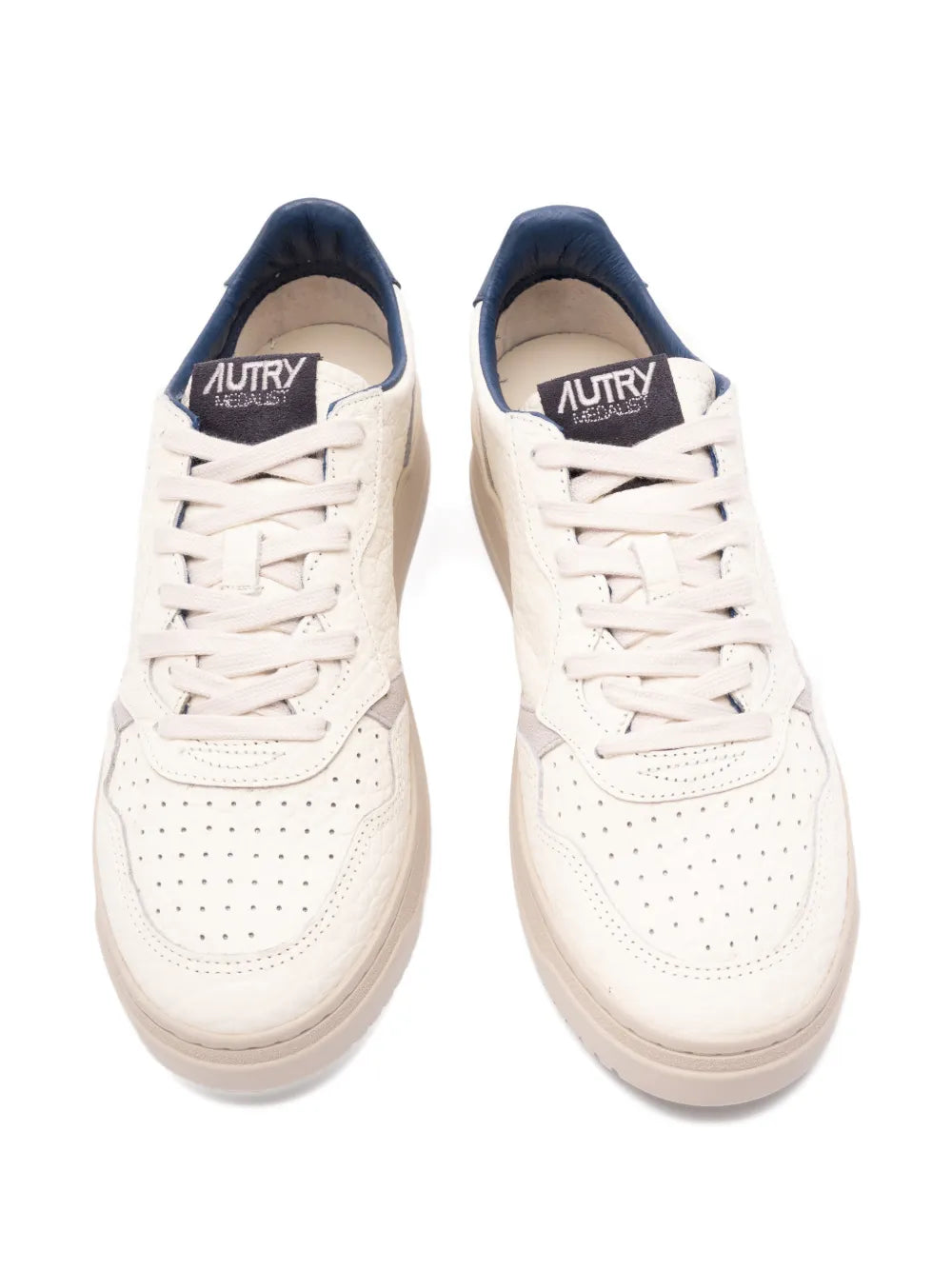Light beige leather-look sneakers with navy collar, white laces, and perforated toe