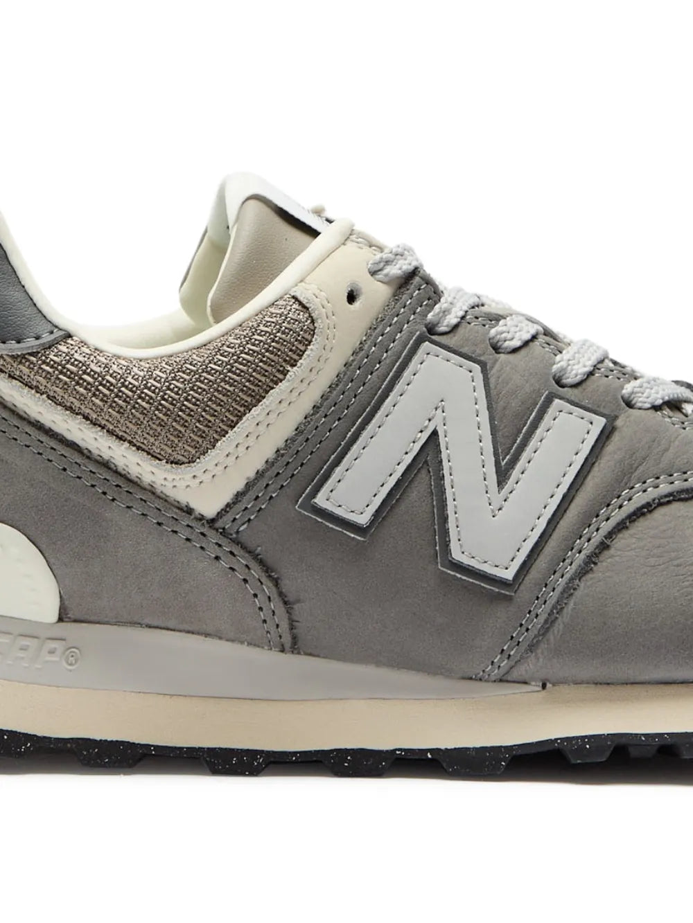 New Balance 574 lace-up sneakers close-up: grey leather panels, white trim, N logo, laces