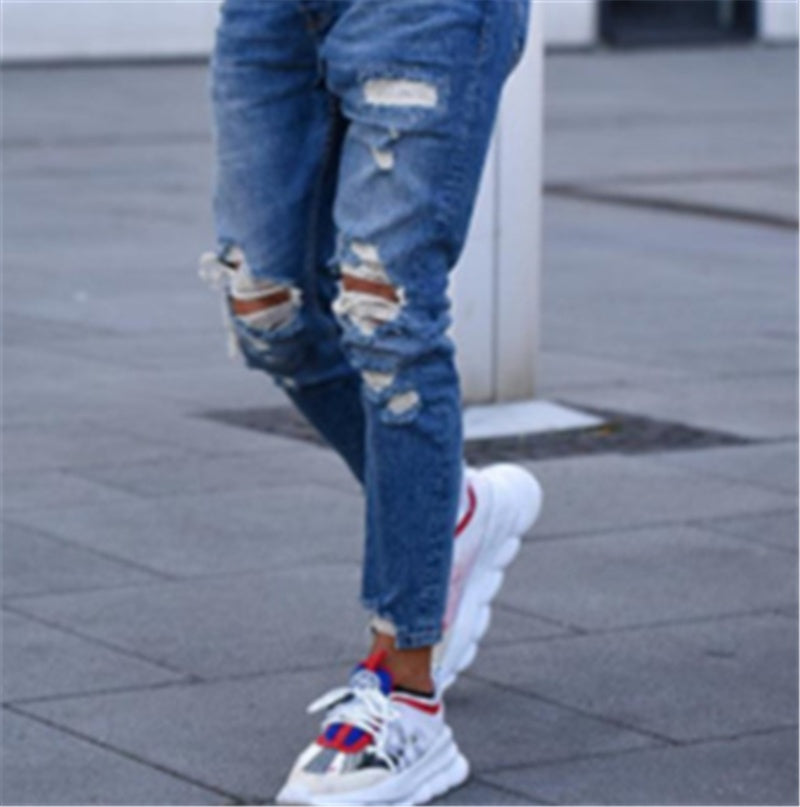 Deep blue ripped jeans with distressed patches at knees and scuffed leg rips