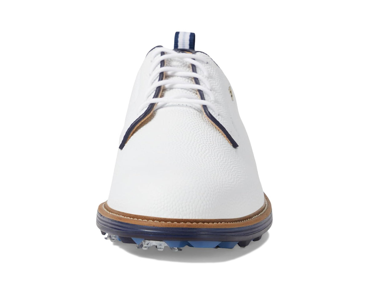 White golf shoe front with navy heel tab and brown welt, blue spiked sole