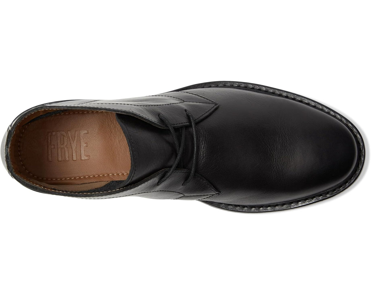 Black chukka boot side view with lace-up top and brown lining at opening
