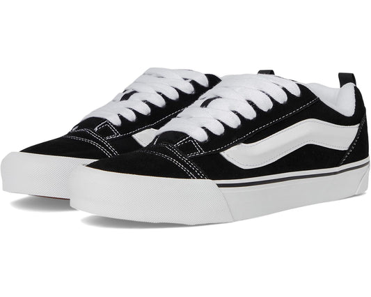 Black and white low-top lace-up sneakers with Vans side stripe and white laces
