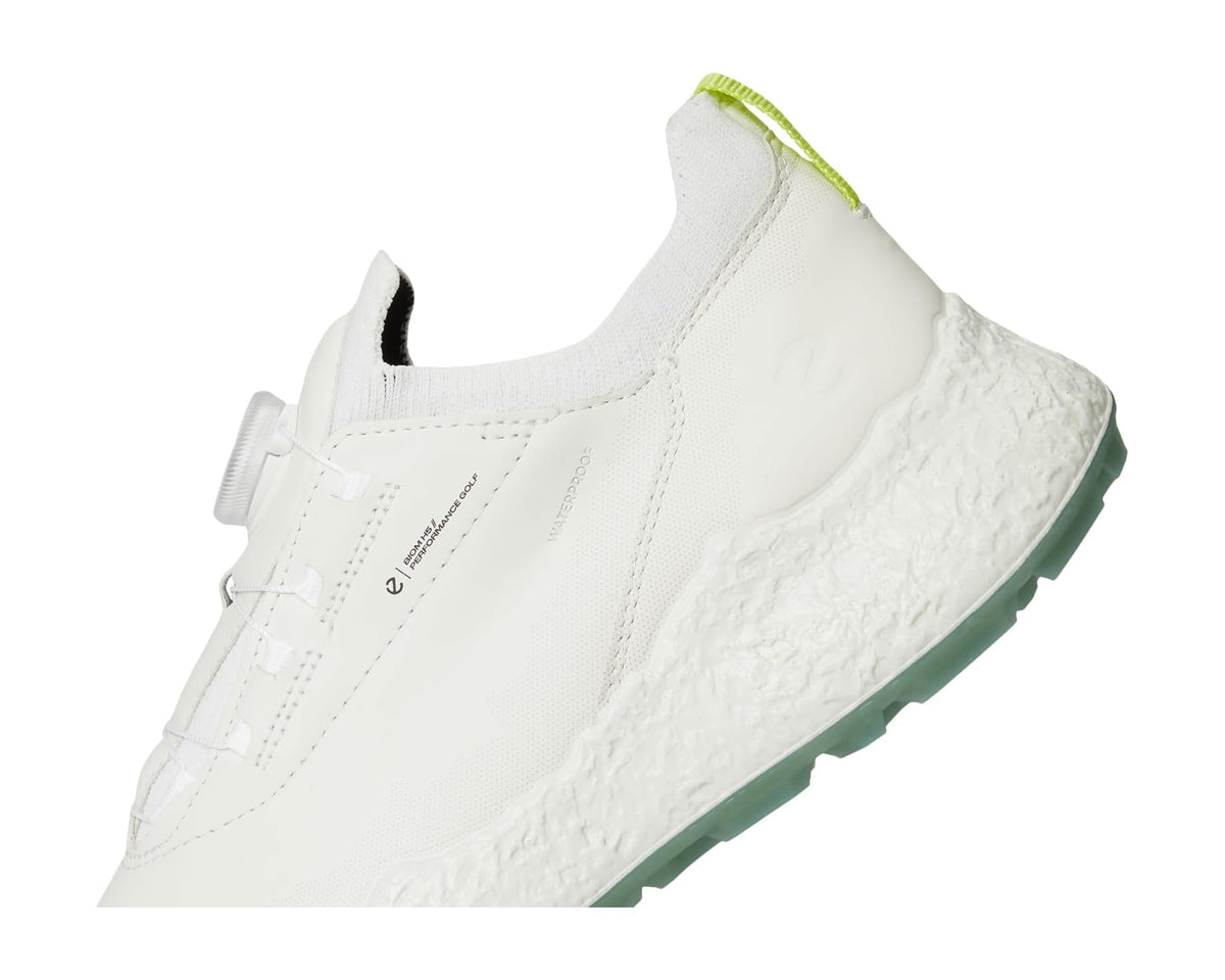 White waterproof golf shoe upper close-up with BOA dial, stitching, and green sole edge