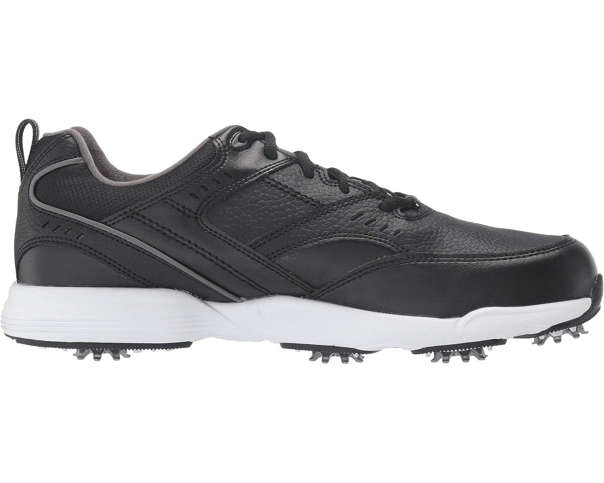 Black golf sneaker side profile with stitched overlays and white spiked outsole