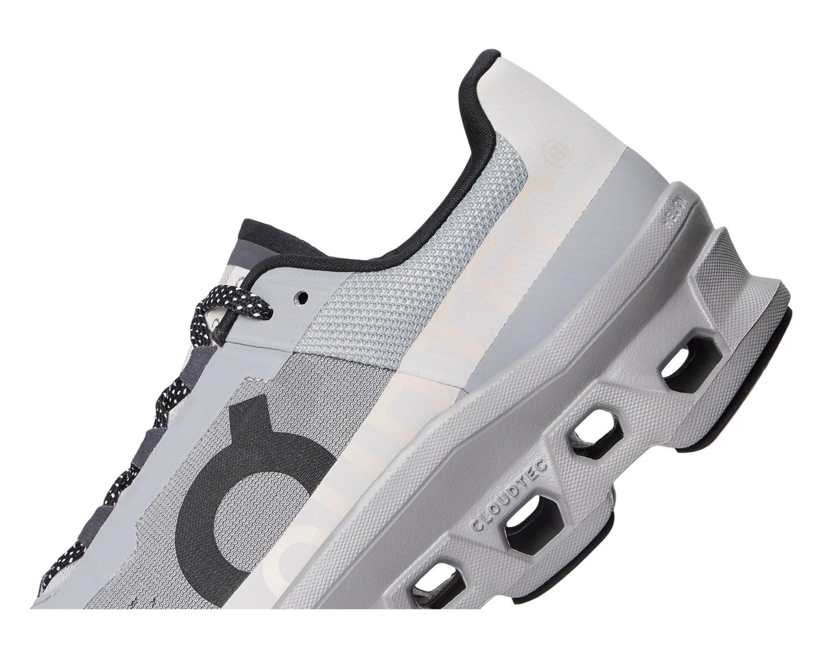 Side view of gray running shoe with black logo, lace-up, and podded outsole