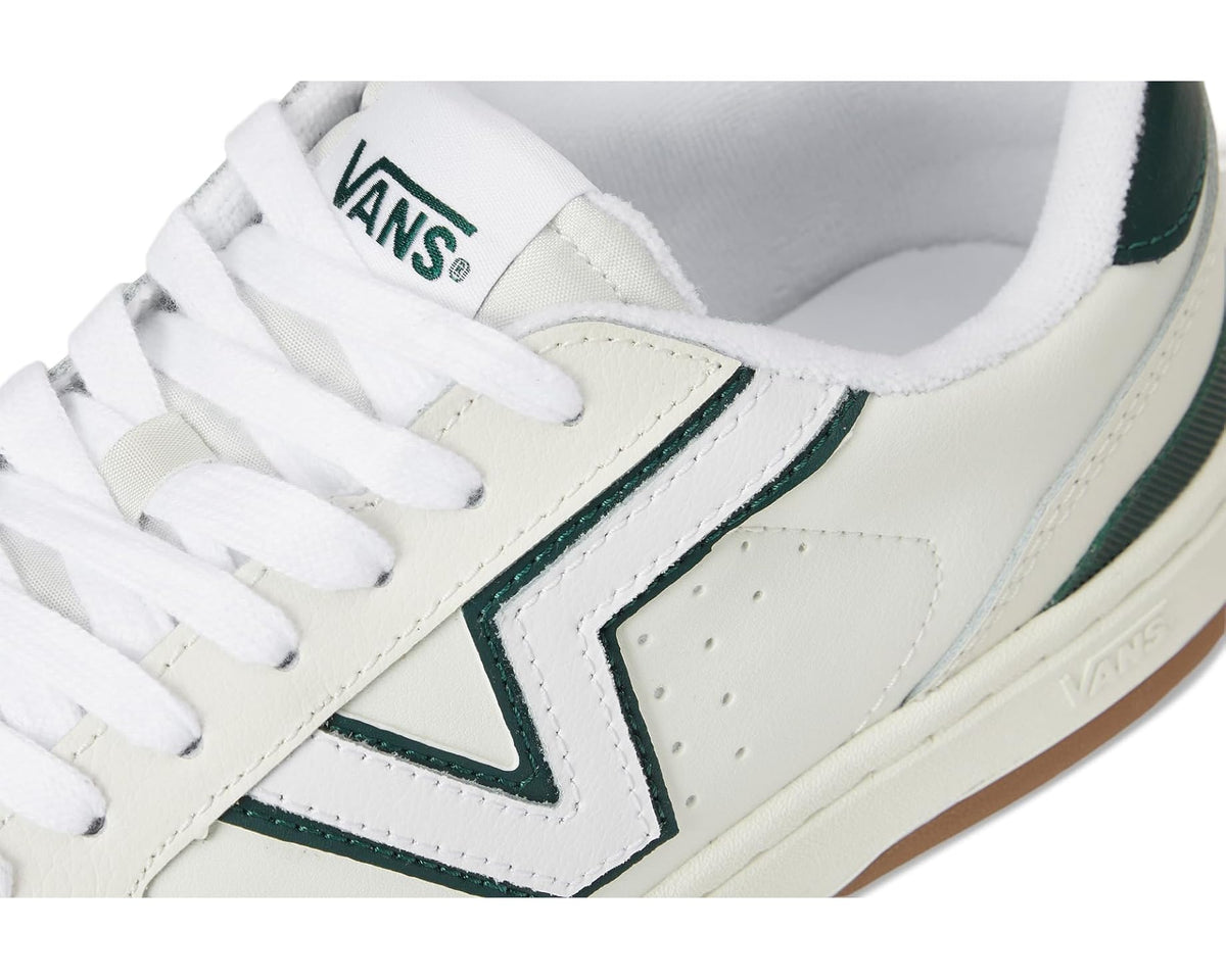 Vans unisex low-top sneaker close-up: white leather, dark green V trim, and cushioned tongue.