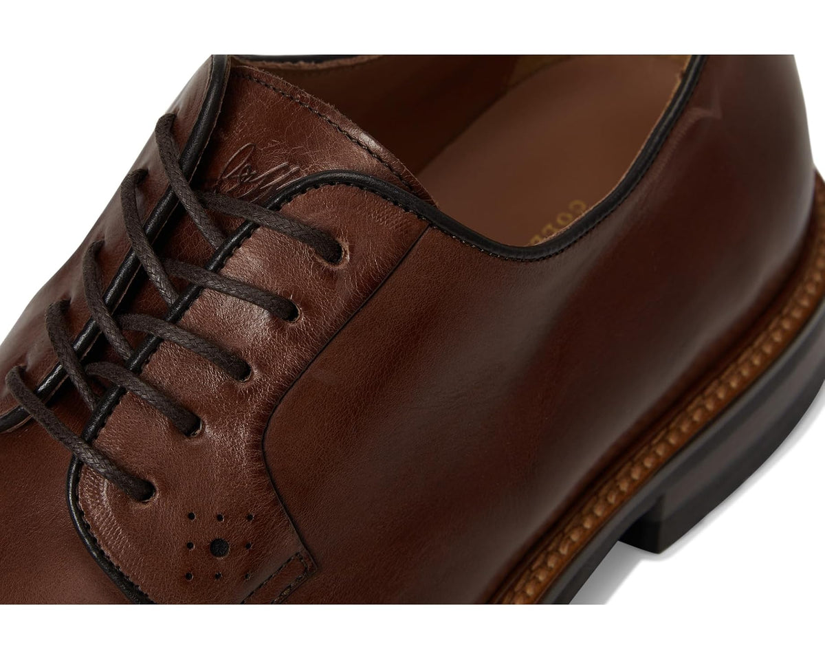 Men's tan leather oxford shoe close-up, lace eyelets and stitched seam details