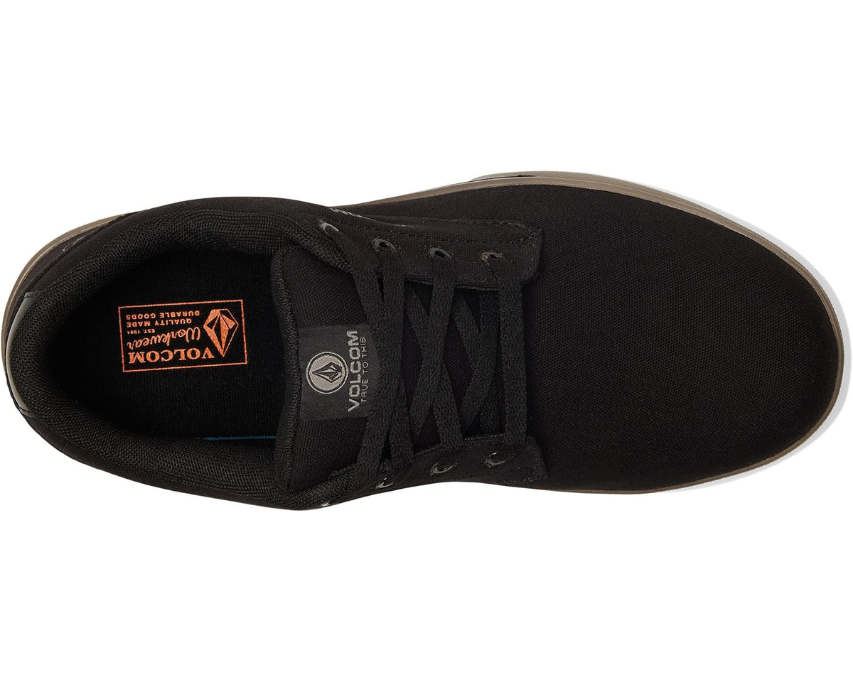 Black sneaker with lace-up front and interior label visible