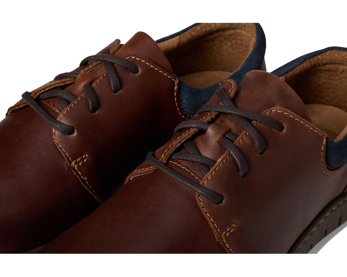 Born men's lace-up shoe close-up: dark brown leather, blue trim, tan stitched seams