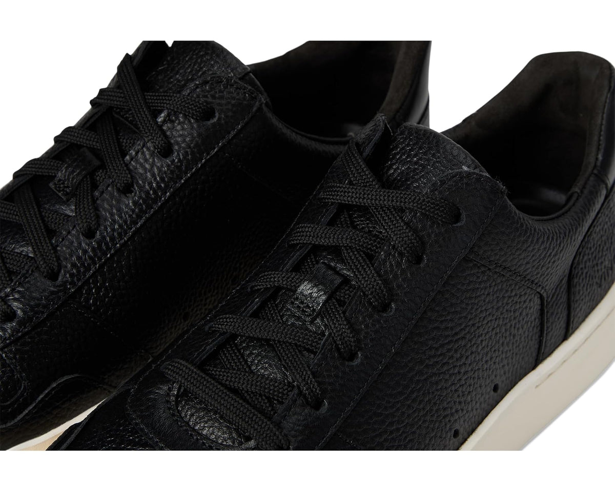 Black leather sneaker close-up showing lace-up, textured upper, and stitching