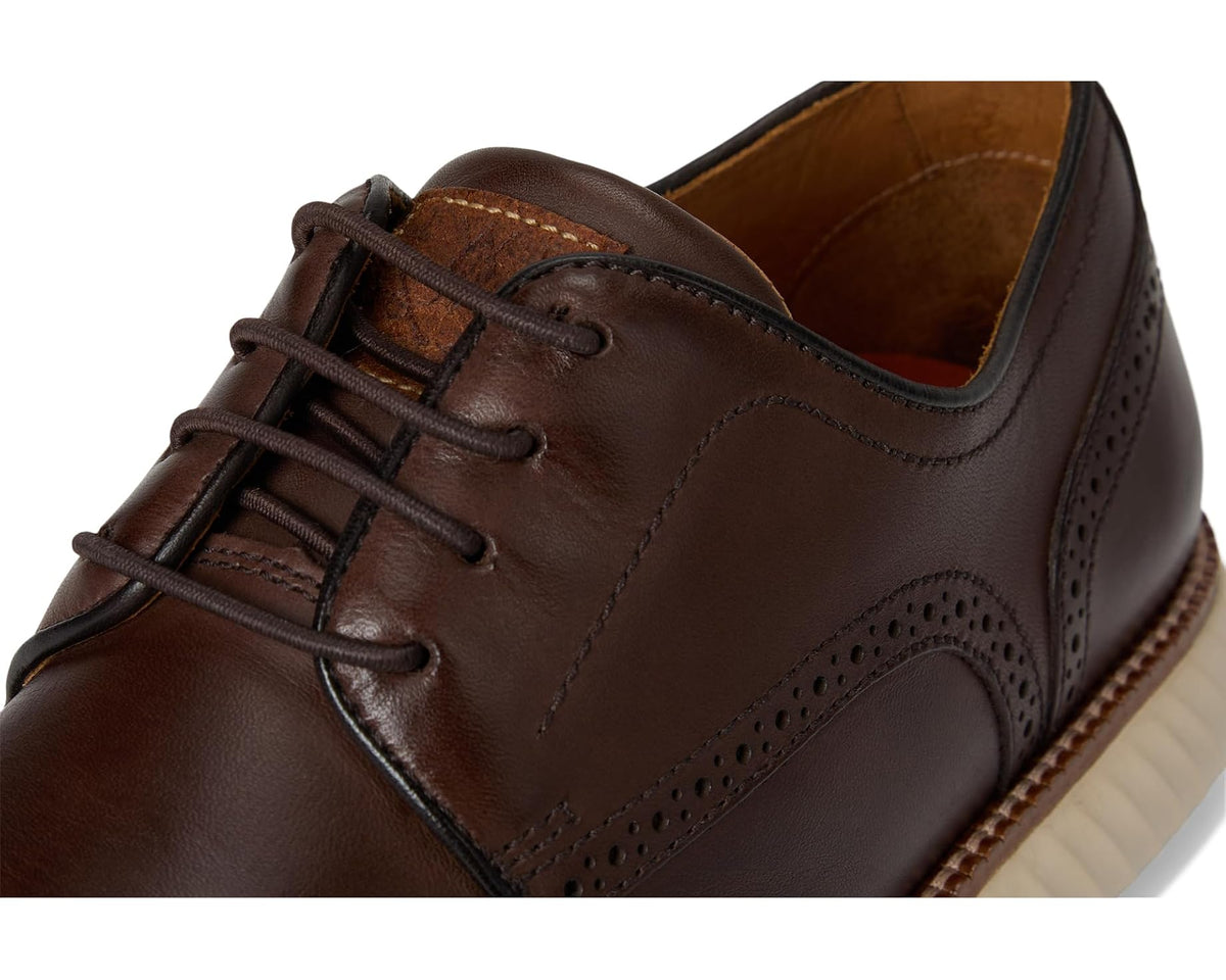 Close-up of chocolate brown leather oxford with lace ties and brogue-style perforations.
