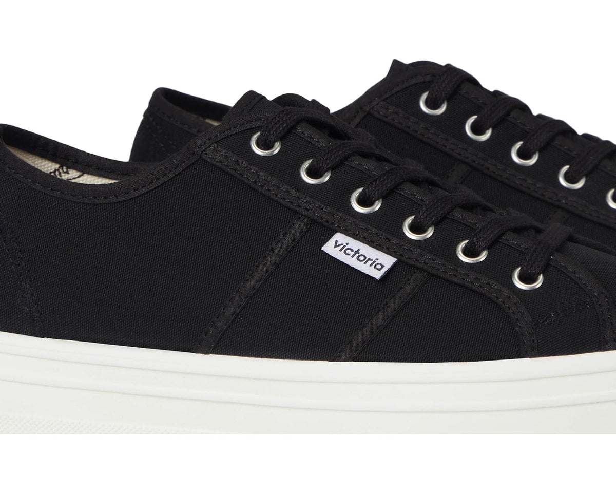 Black canvas sneaker side profile with lace-up eyelets and stitched panels