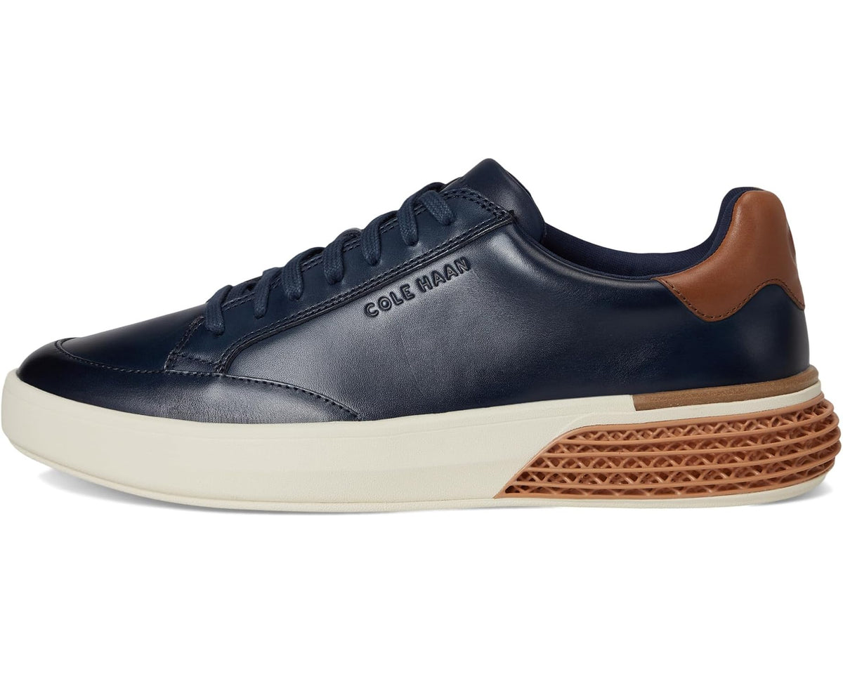 Navy low-top lace-up sneakers with tan heel and brown textured midsole, cream sole.