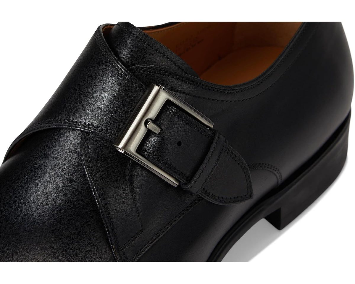 Black leather men's dress shoe buckle and strap close-up, metallic buckle.