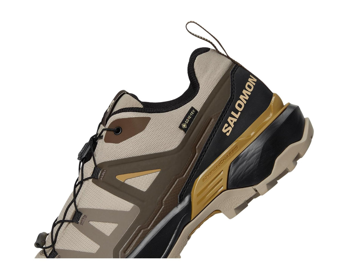 Men's khaki trail shoe side view with Salomon branding, lace-up, and protective overlays