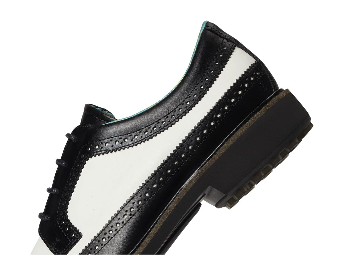 Men's ECCO wingtip golf shoe close-up, black and white leather with brogue stitching