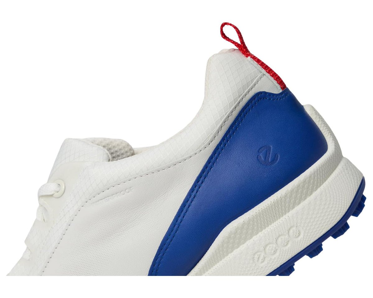 Side close-up of white and blue golf sneaker with red lace pull and cushioned collar