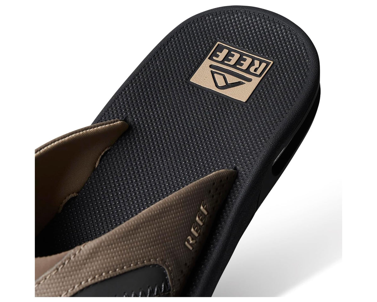 Black flip-flop footbed with beige logo patch and strap opening