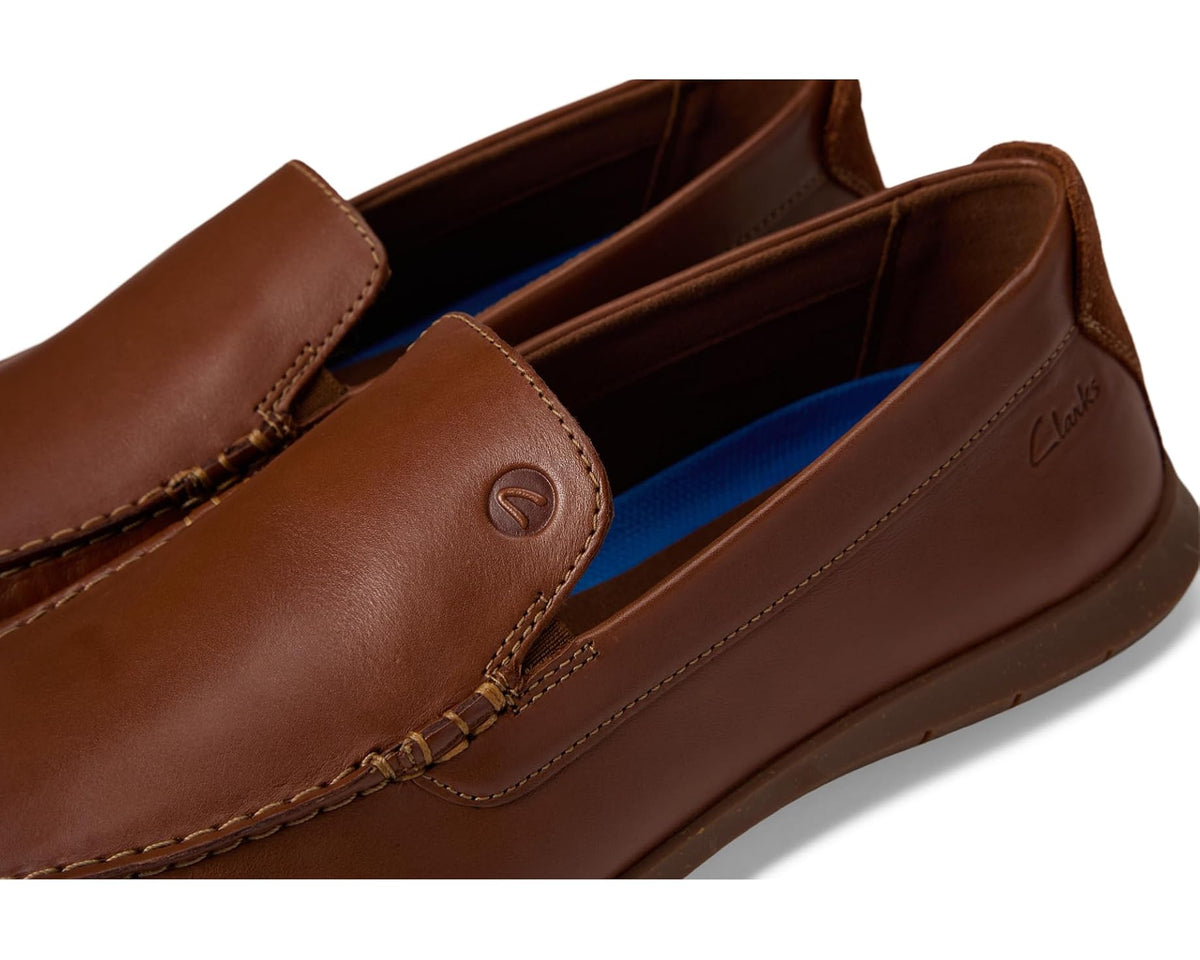 Men's tan loafer close-up of leather vamp, logo detail, and blue lining