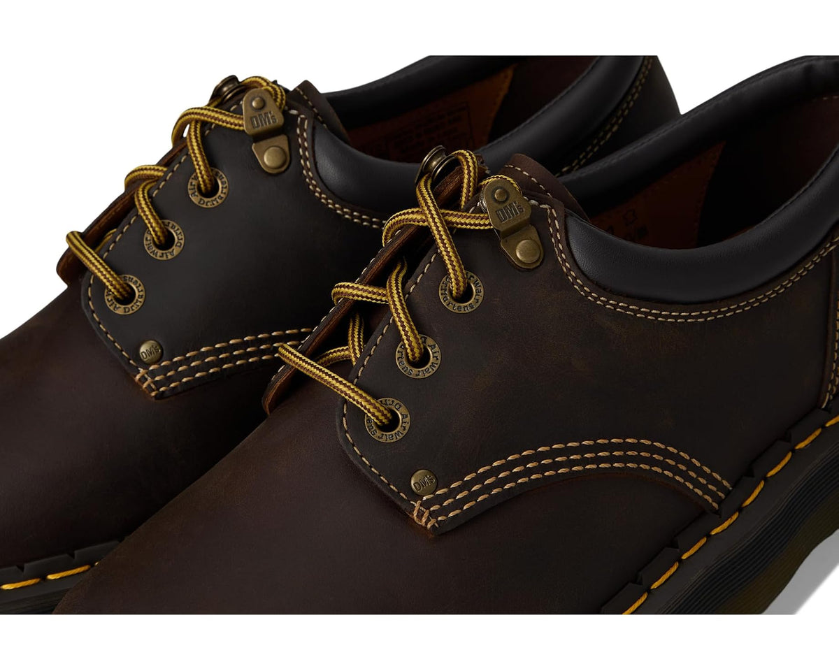 Close-up of dark brown leather lace-up shoe with eyelets and yellow stitching