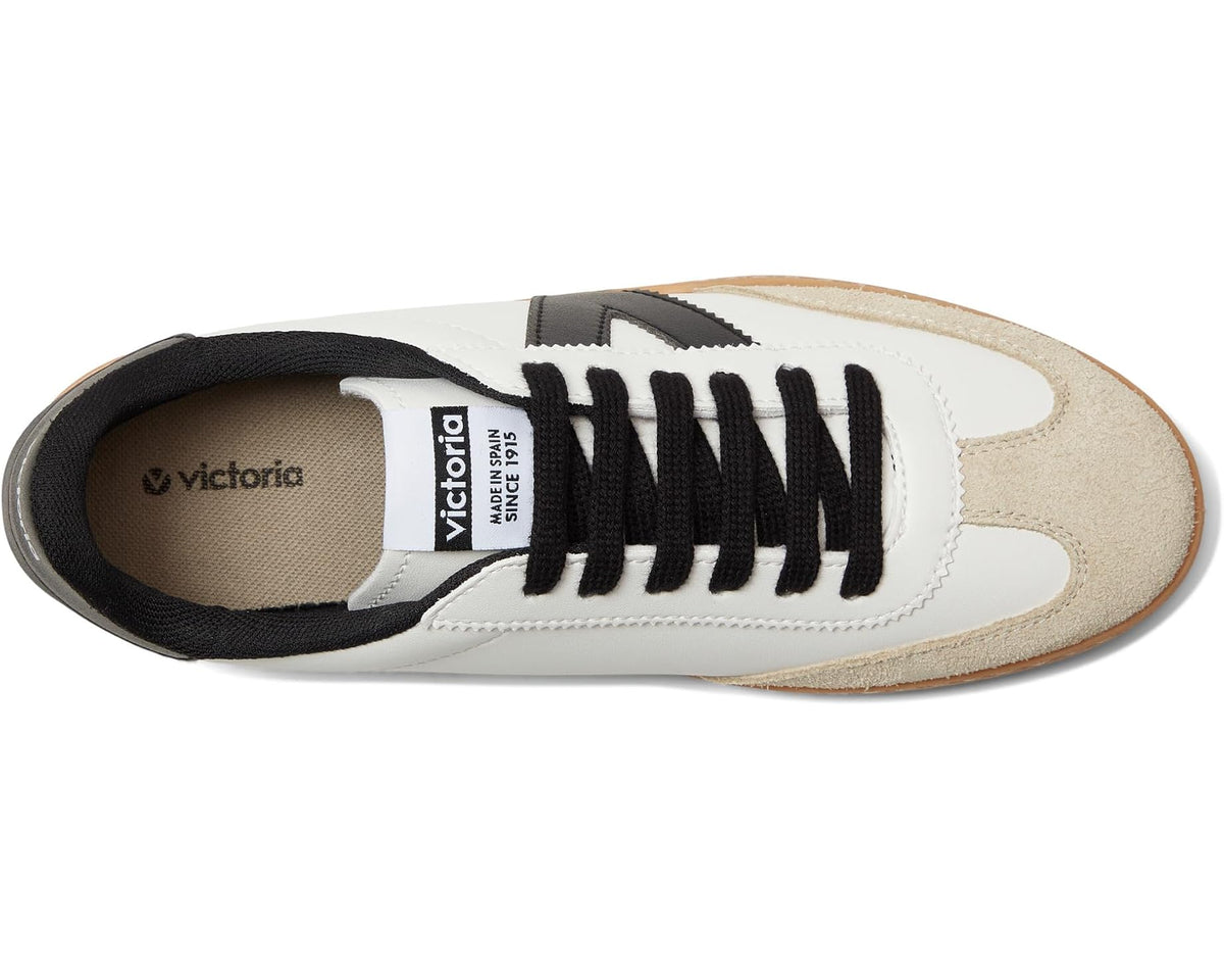 Low-top sneaker side view: white upper, beige suede toe, black laces, tan gum sole