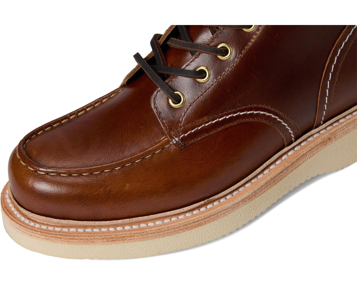 Brown leather workboot close-up with stitched moc toe and lace hardware