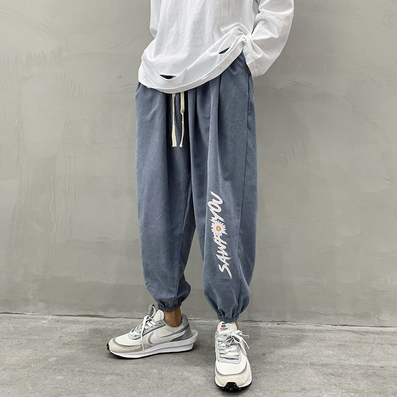 Blue jogger trousers with drawstring waist, relaxed tapered legs, white script print