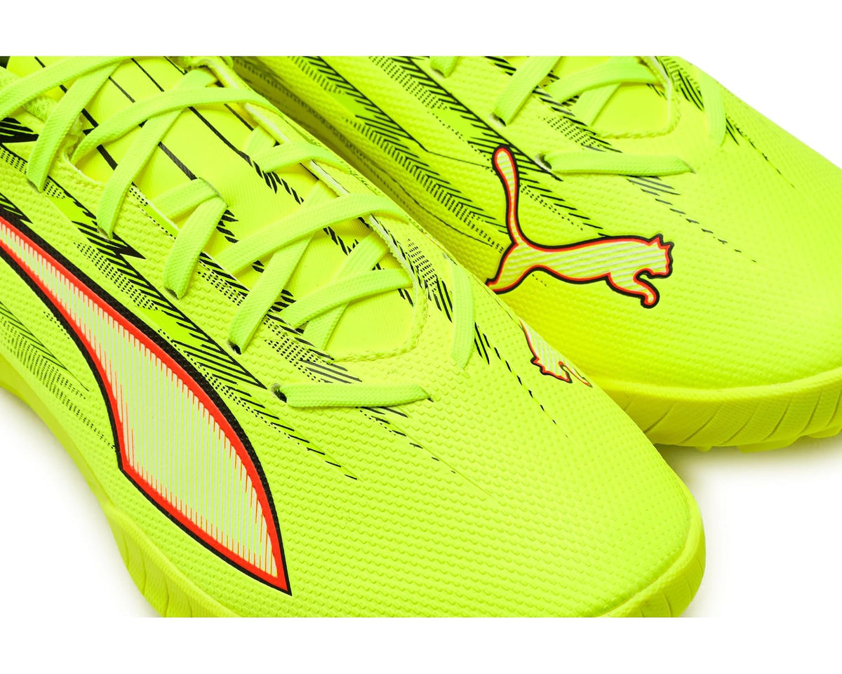 Neon yellow lace-up turf cleat close-up with PUMA cat logo and red stripe