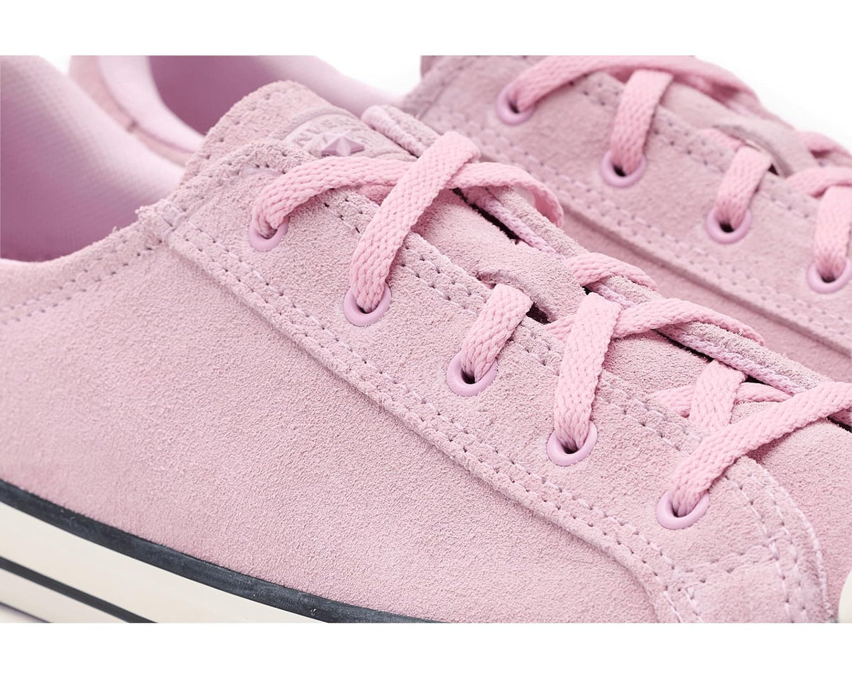 Close-up of pink suede sneaker with lace-up eyelets and stitched panel details