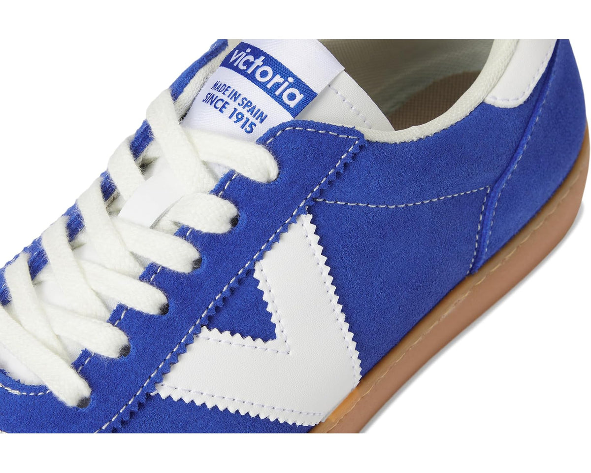 Royal blue suede sneaker close-up with white logo tongue label and lace detail