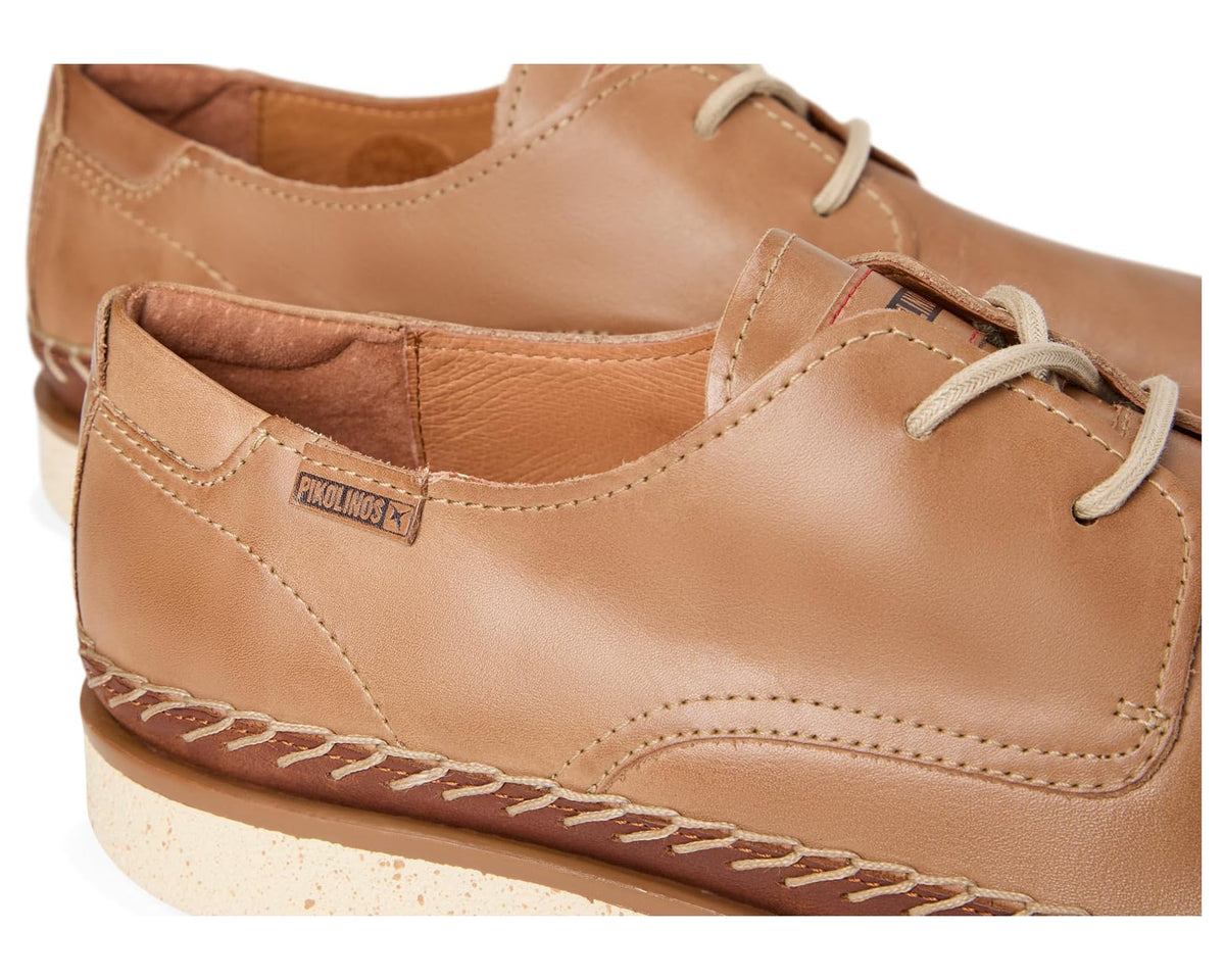 Close-up of tan leather lace-up shoe with stitched seams and lace eyelets