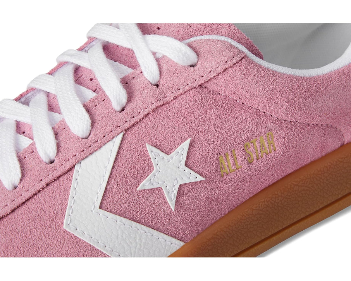 Close-up of pink suede sneaker side with white star, All Star text, and gum edge