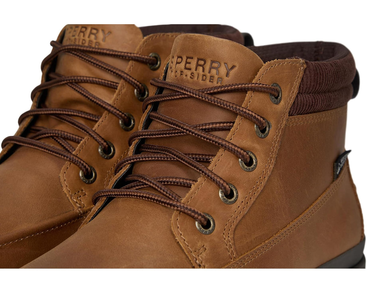 Tan moc boot close-up showing lace-up front, stitched panels, and padded tongue logo