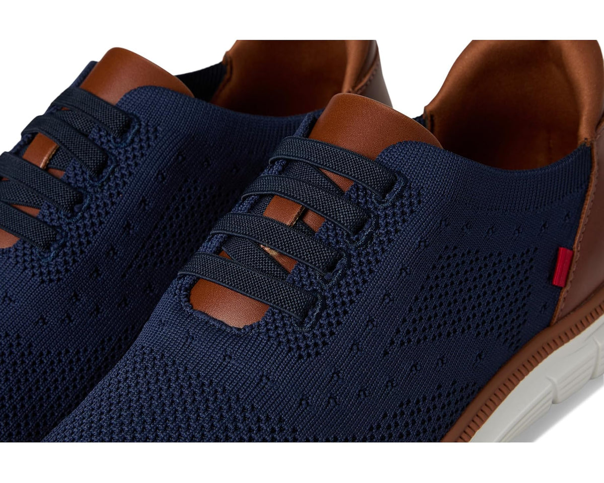 Close-up of navy knit upper, lace loops, and brown leather collar with red tag