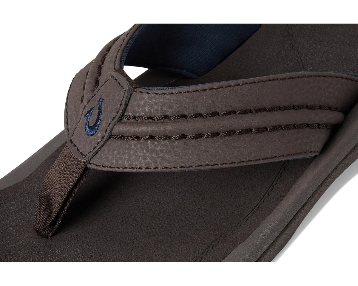 OluKai men’s dark brown flip-flop close-up of stitched strap and blue logo