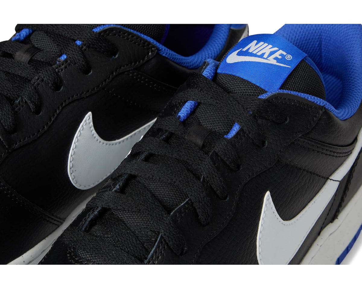 Nike low-top sneaker close-up: black lace-up upper with white swoosh and blue hits.
