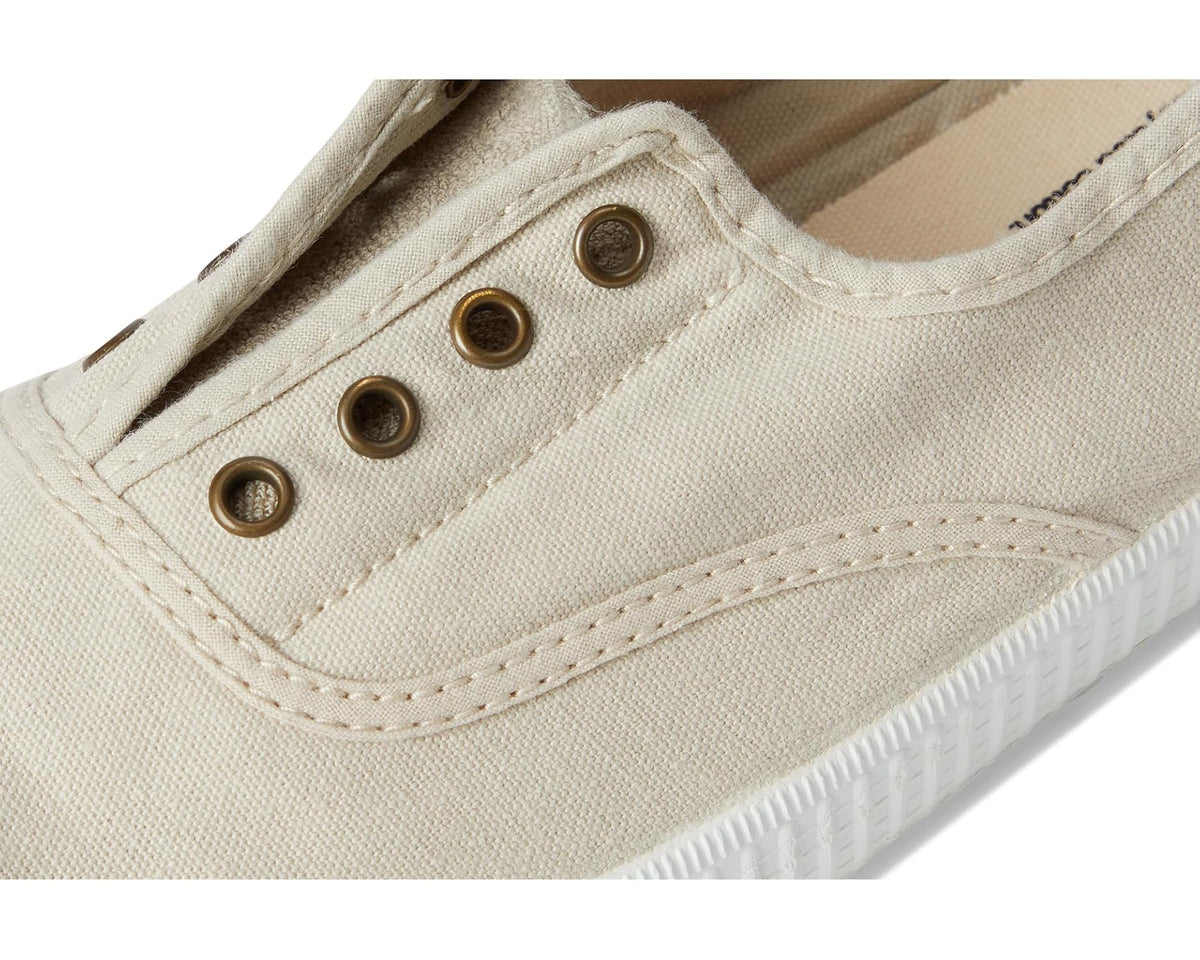 Women's beige canvas sneakers, close-up of stitching and metal eyelets