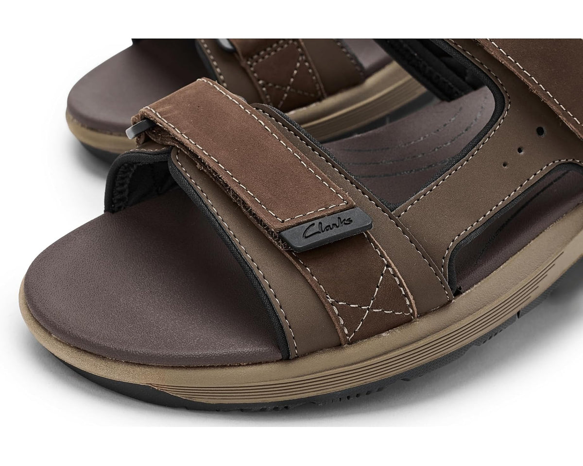 Brown leather sandal strap close-up with stitching and Clarks logo patch