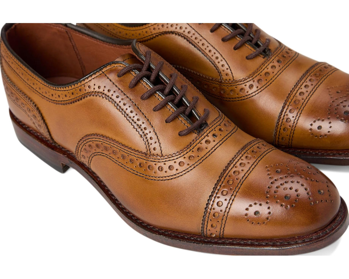 Men's walnut-brown leather oxford shoe close-up of brogue perforations and laces